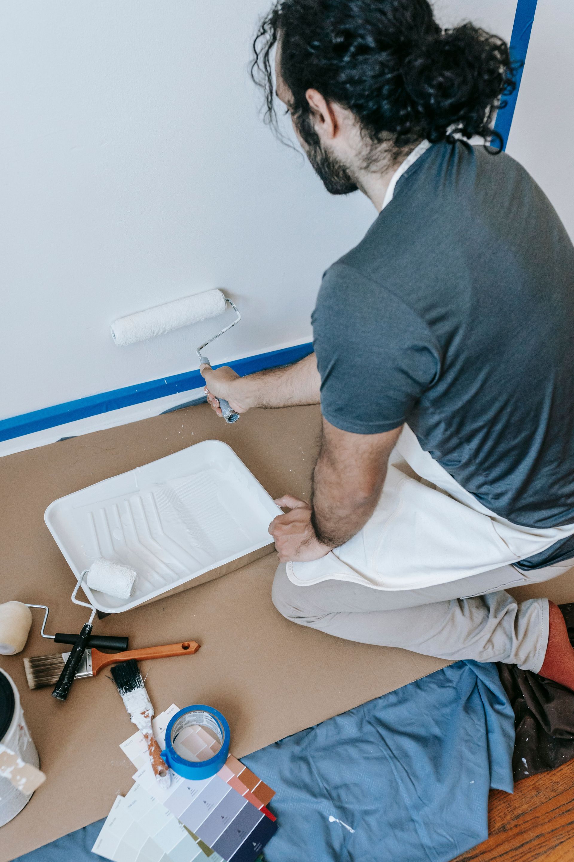 A man using a roller to paint a wall while renovating his home.